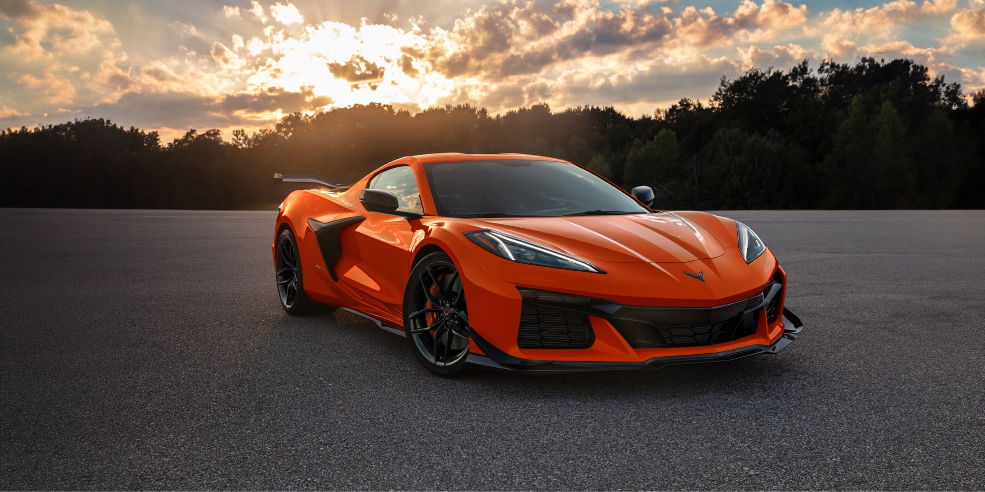 Three Quarters View of an Orange 2026 Chevy Corvette Z06 with a Setting Sun Behind It