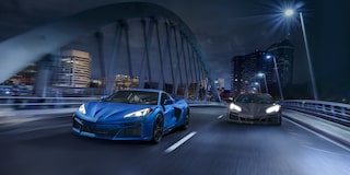 Front View of a 2025 Blue and Gray Chevy Corvette E-Ray Racing Down the Road on a Bridge