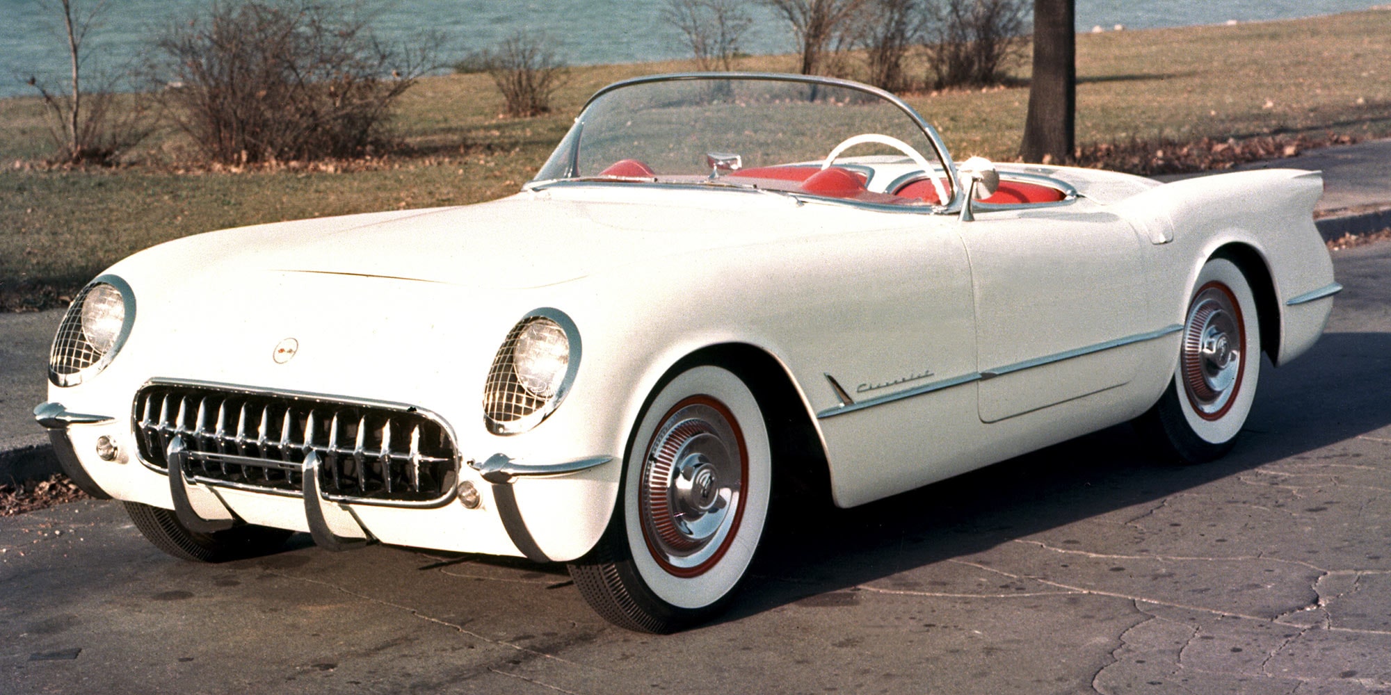Frontansicht einer silbernen klassischen Corvette mit Klappscheinwerfern und Chromakzenten, im Freien geparkt.