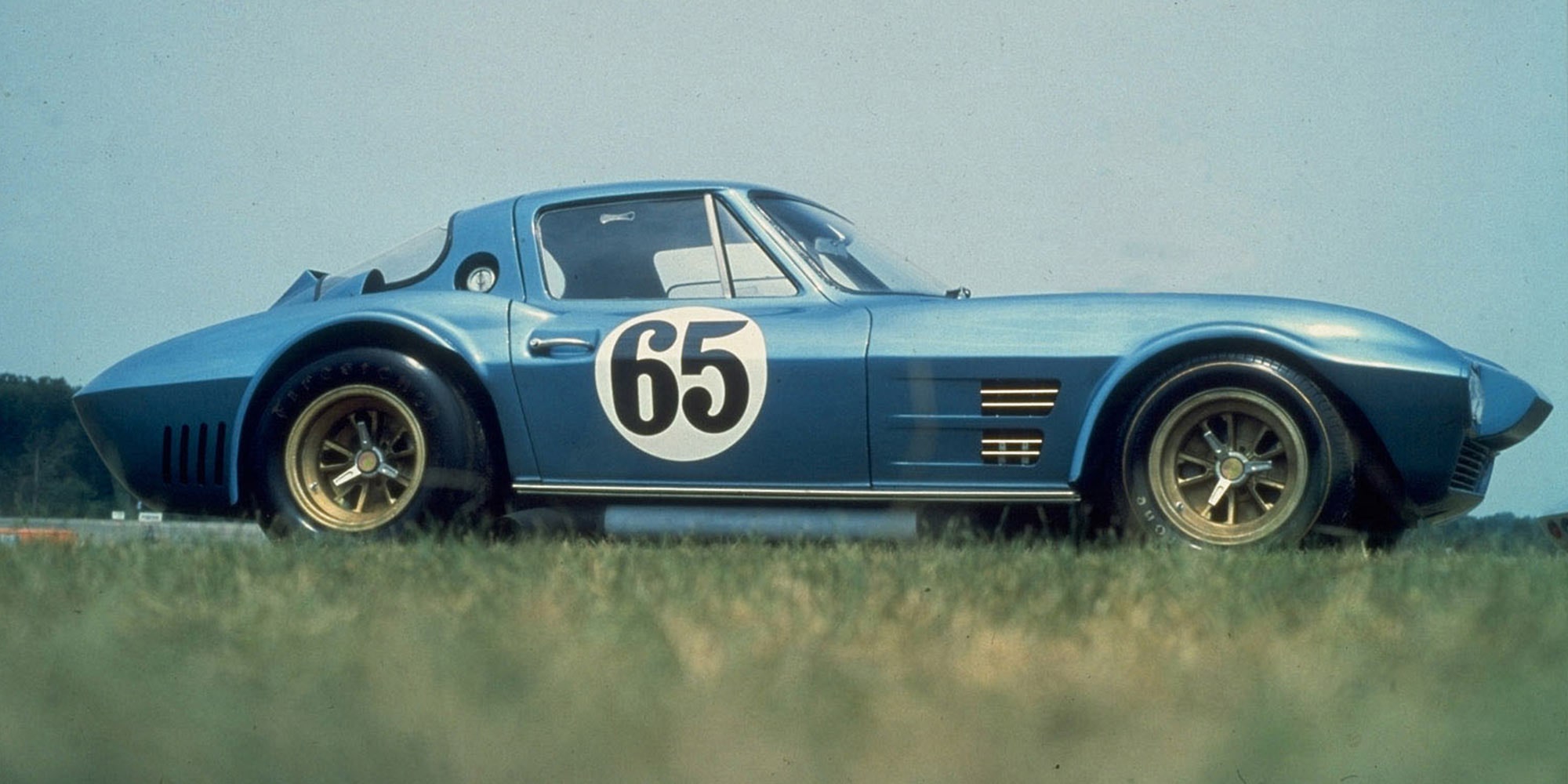Seitenansicht einer metallicblauen Corvette Grand Sport von 1963 mit der Startnummer 65 auf der Tür.