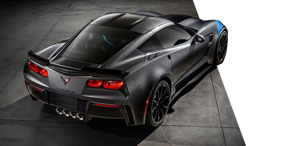 Three-quarter rear view of a black Chevrolet Corvette C8 coupé, parked on cement.