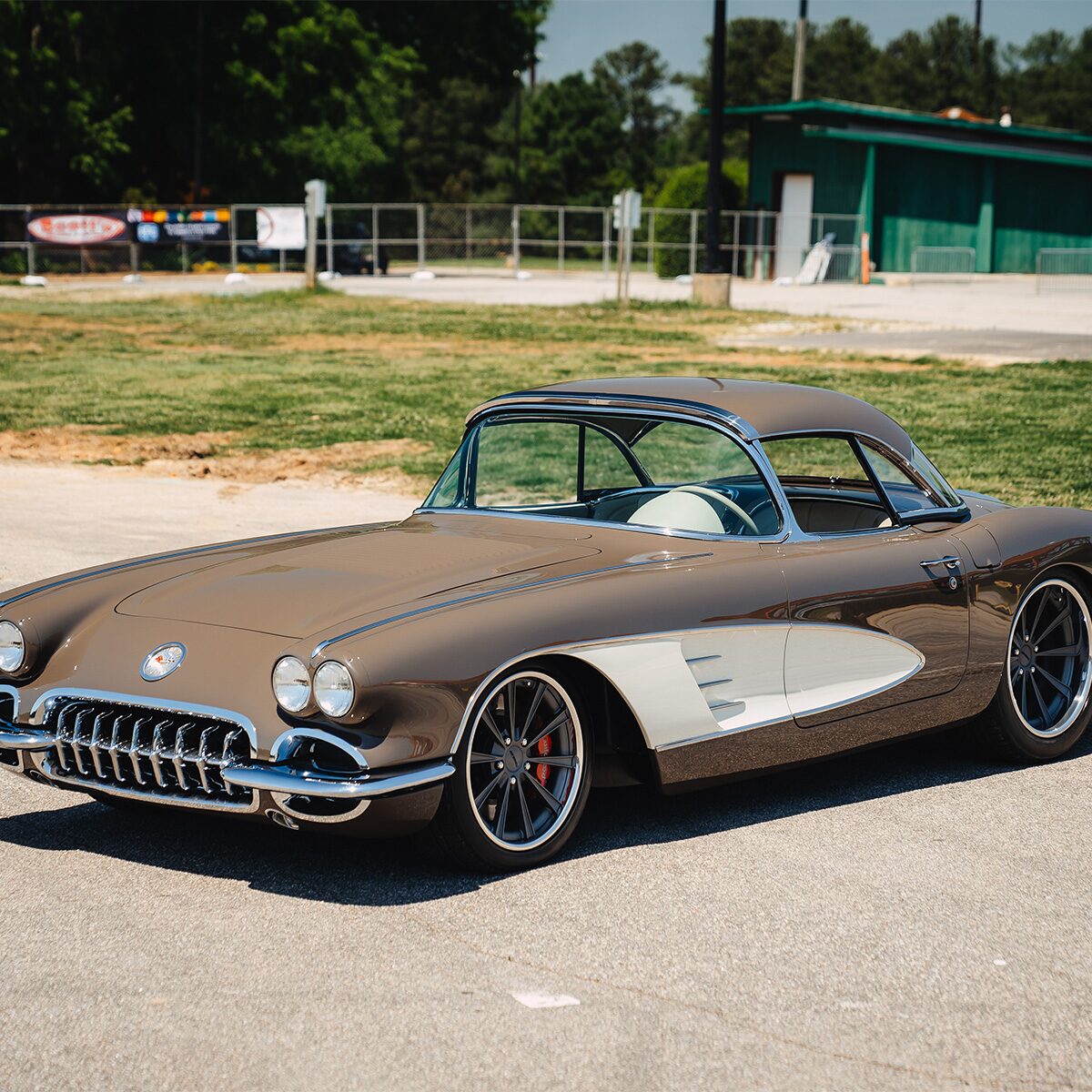 Three-quarter view of a 2-tone brown and white 1958 Corvette convertible with chrome trim and polished wheels, parked outdoors.