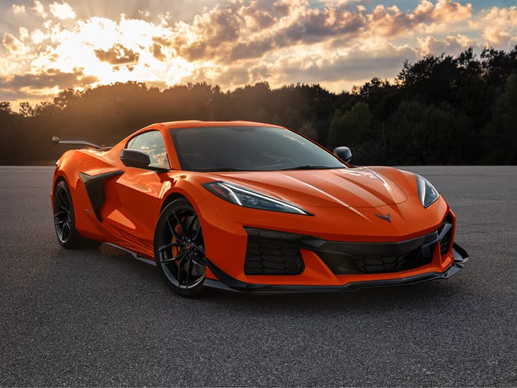 Three-quarter view of a 2026 Chevy Corvette Z06 in Sebring Orange Tintcoat, parked at dusk.